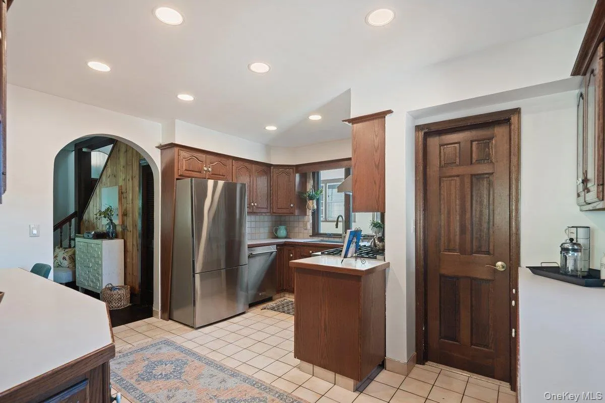 The arched doorway leads to the living room, while an updated powder room sits behind the wooden door, accessible from the kitchen. The arched doorway leads to the living room, while an updated powder room sits behind the wooden door, accessible from the kitchen.