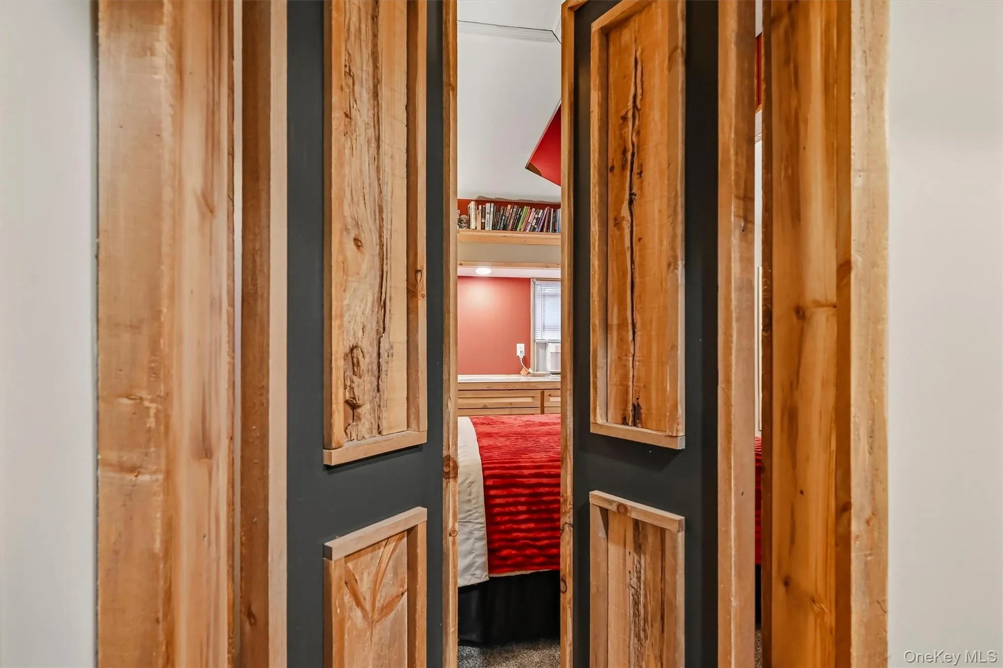 Wood-paneled double doors open to reveal built-in shelving, recessed lighting, and a window with a valance Wood-paneled double doors open to reveal built-in shelving, recessed lighting, and a window with a valance
