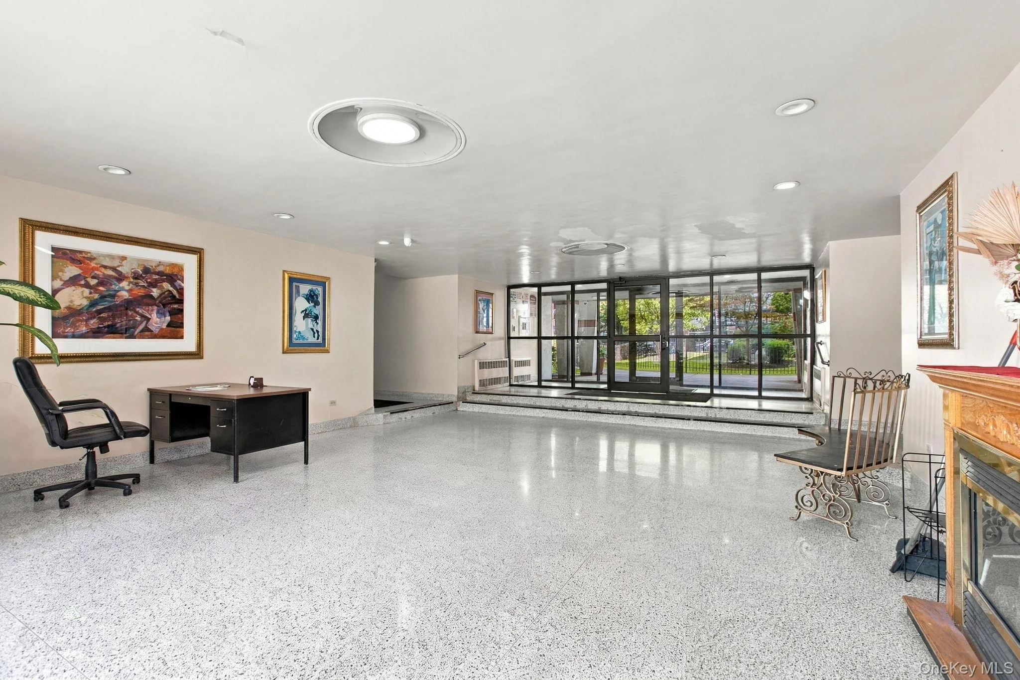 Spacious entry area featuring polished terrazzo flooring, recessed lighting, and a large glass-paneled entrance Spacious entry area featuring polished terrazzo flooring, recessed lighting, and a large glass-paneled entrance