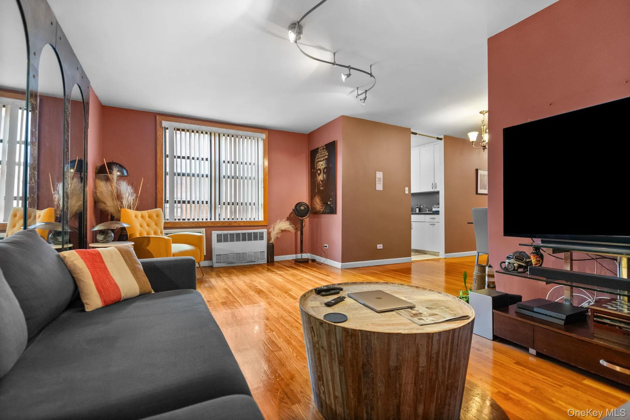 Hardwood flooring throughout, track lighting, and a window with vertical blinds Hardwood flooring throughout, track lighting, and a window with vertical blinds