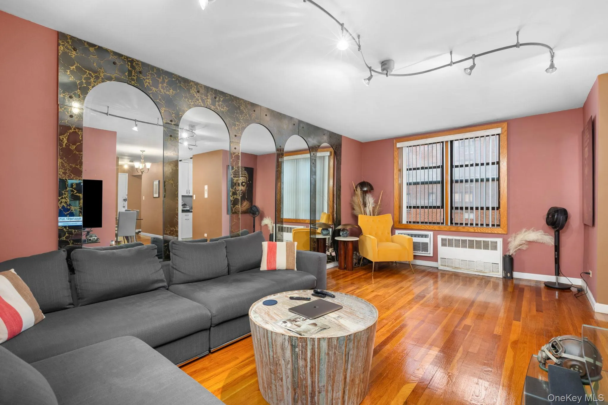 Hardwood flooring, arched mirrored wall feature, track lighting, window with blinds, and wall-mounted air conditioning units Hardwood flooring, arched mirrored wall feature, track lighting, window with blinds, and wall-mounted air conditioning units