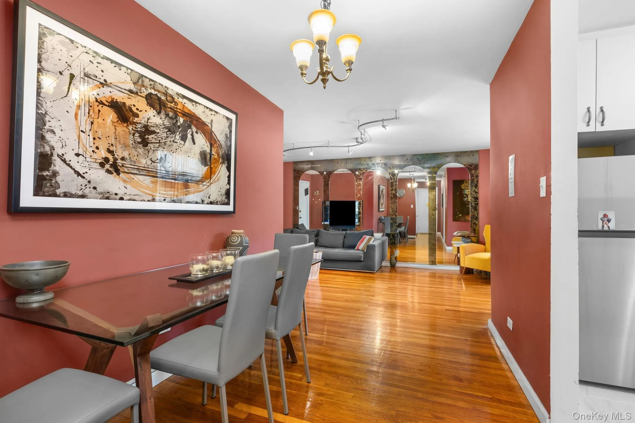 Hardwood flooring throughout, recessed archways, track lighting, and a chandelier with glass shades Hardwood flooring throughout, recessed archways, track lighting, and a chandelier with glass shades