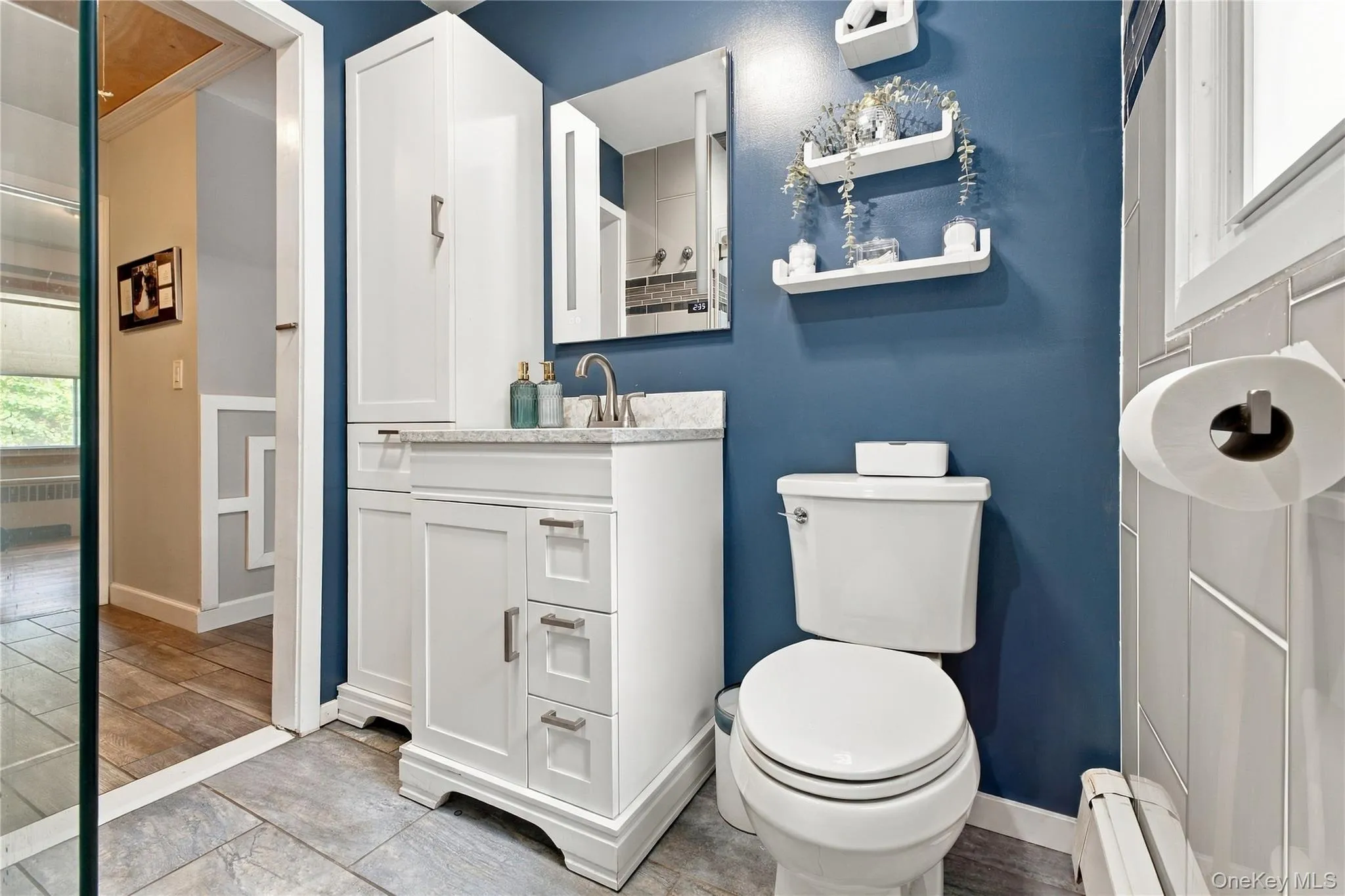 Updated primary bathroom with ceramic tile floor and glass tile walls in shower Updated primary bathroom with ceramic tile floor and glass tile walls in shower
