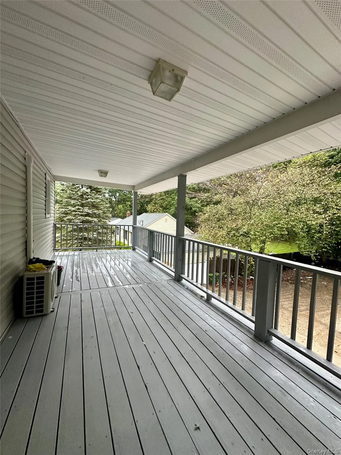 Covered balcony featuring painted wood-finish decking, structural support posts, and a full-length railing Covered balcony featuring painted wood-finish decking, structural support posts, and a full-length railing