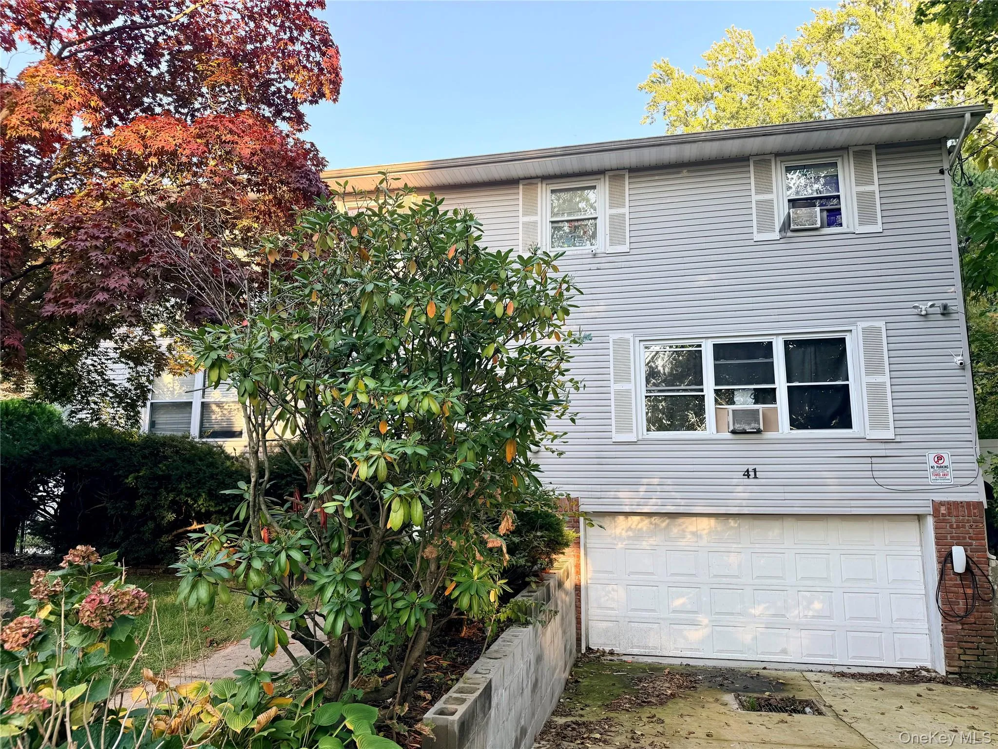 Two-story exterior featuring light-toned horizontal siding, decorative window shutters, a paved driveway, and an attached two-car garage Two-story exterior featuring light-toned horizontal siding, decorative window shutters, a paved driveway, and an attached two-car garage