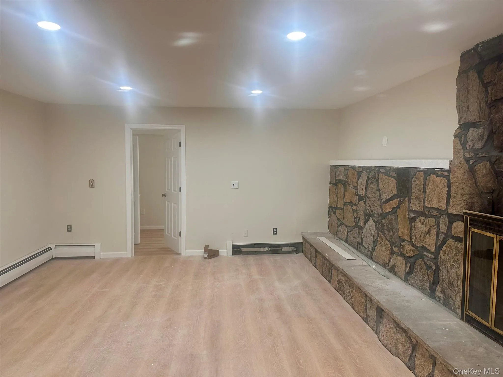 Stone fireplace with a raised hearth, wood-finish flooring, and recessed ceiling lighting Stone fireplace with a raised hearth, wood-finish flooring, and recessed ceiling lighting