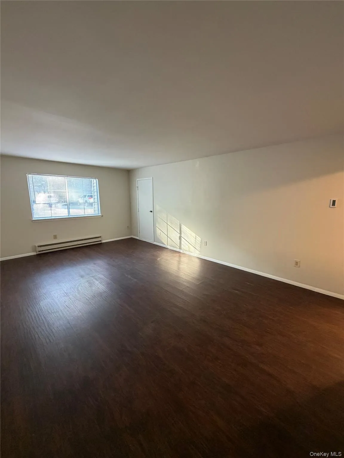 Wood-finish flooring throughout, window with horizontal blinds, and a built-in wall heater. Wood-finish flooring throughout, window with horizontal blinds, and a built-in wall heater.