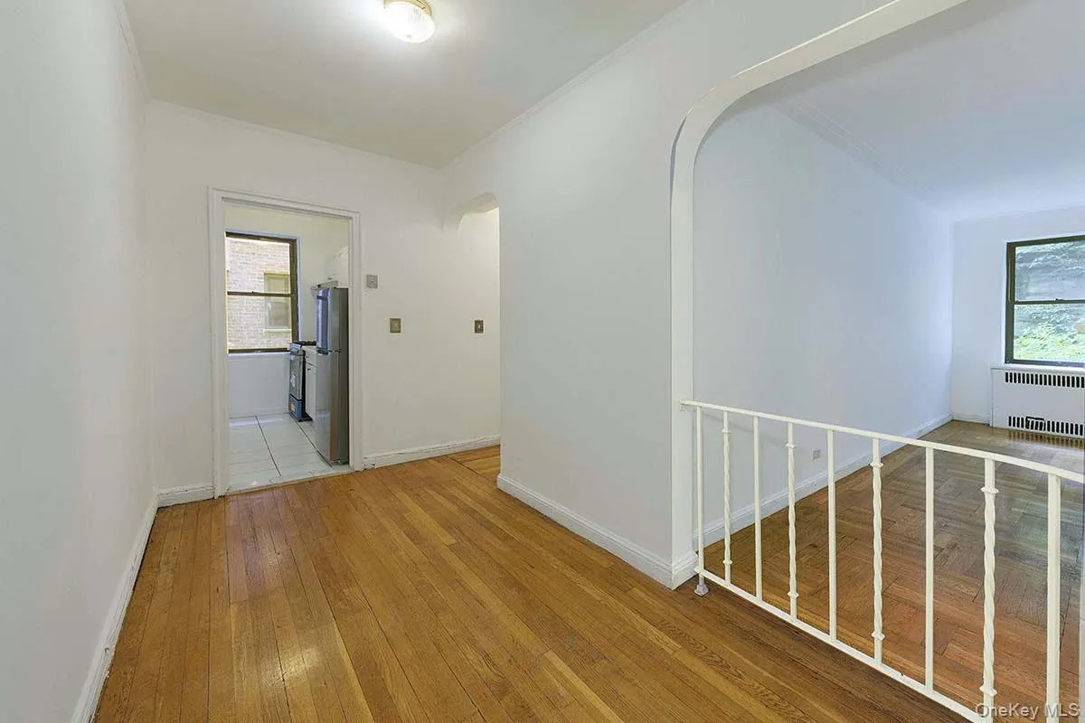 Wood-finish flooring, decorative arched architectural detail, white metal spindle railing, and clean wall finishes Wood-finish flooring, decorative arched architectural detail, white metal spindle railing, and clean wall finishes