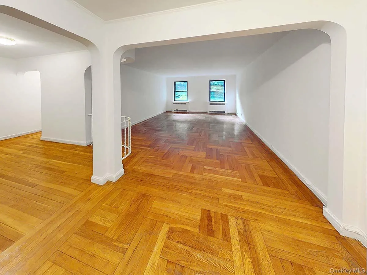 Interior space featuring herringbone wood-finish flooring, rounded architectural archways, and double-hung windows Interior space featuring herringbone wood-finish flooring, rounded architectural archways, and double-hung windows