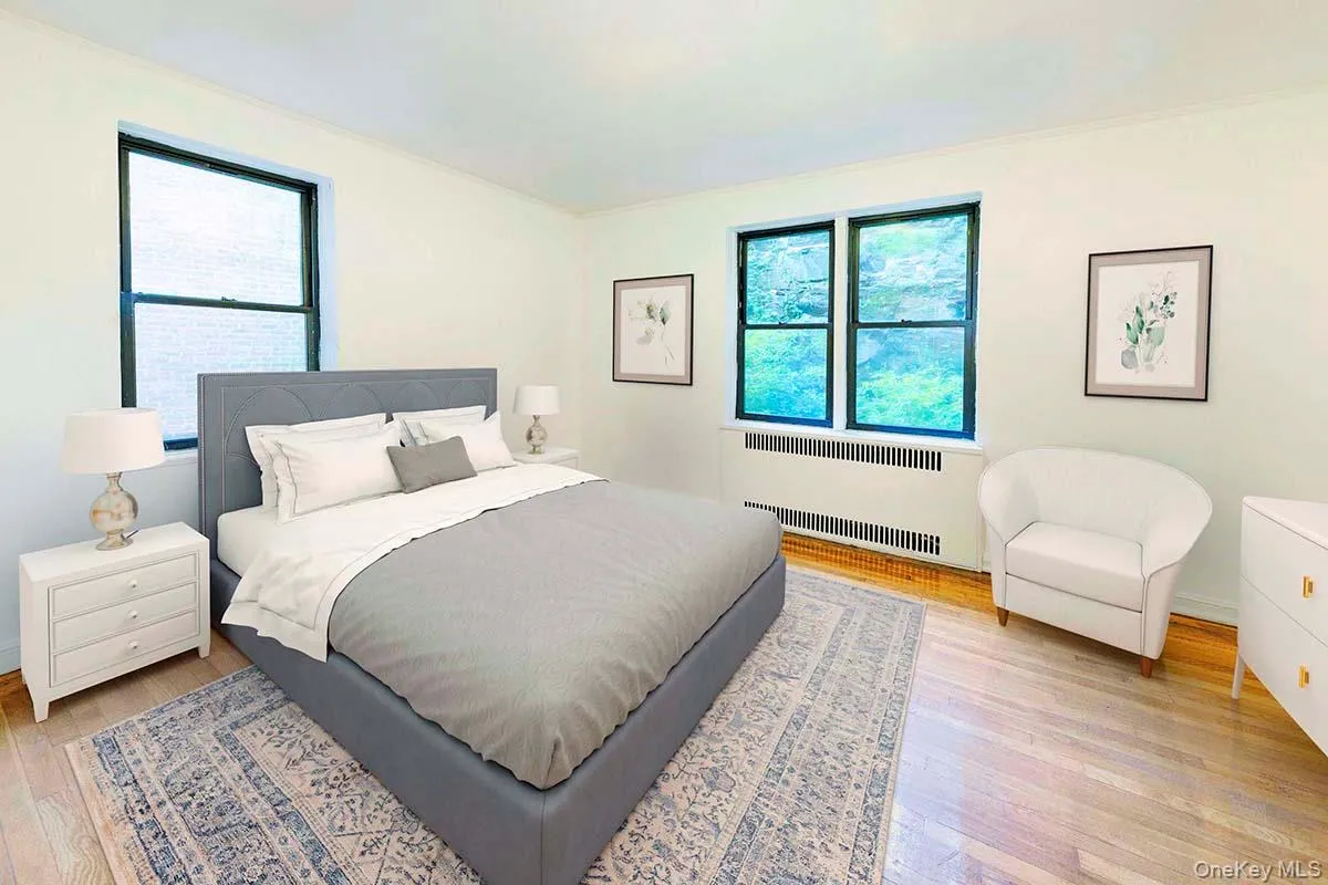 Room featuring wood-finish flooring, dual windows with black frames, and neutral wall tones Room featuring wood-finish flooring, dual windows with black frames, and neutral wall tones