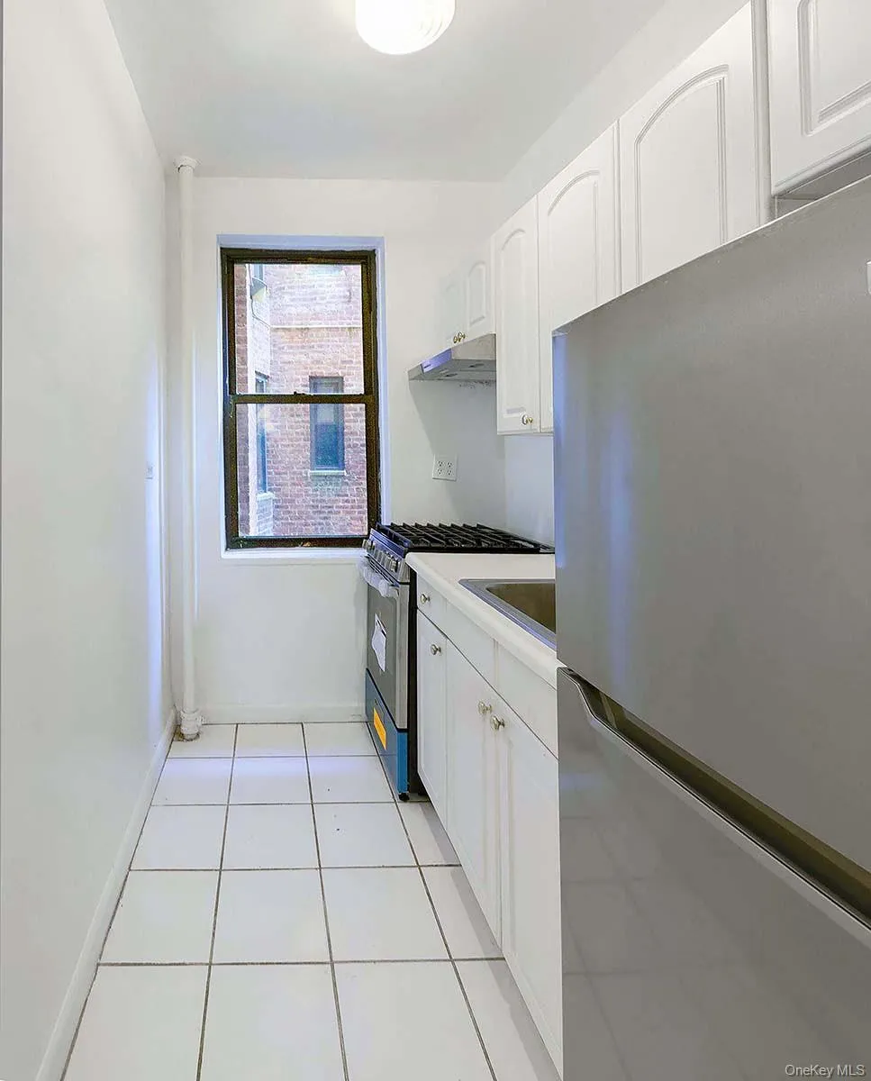 Kitchen featuring white shaker-style cabinetry, stainless steel appliances, ceramic tile flooring, and a window Kitchen featuring white shaker-style cabinetry, stainless steel appliances, ceramic tile flooring, and a window