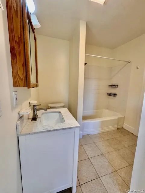 Bathroom with vanity, tile patterned flooring, and shower / bath combination Bathroom with vanity, tile patterned flooring, and shower / bath combination