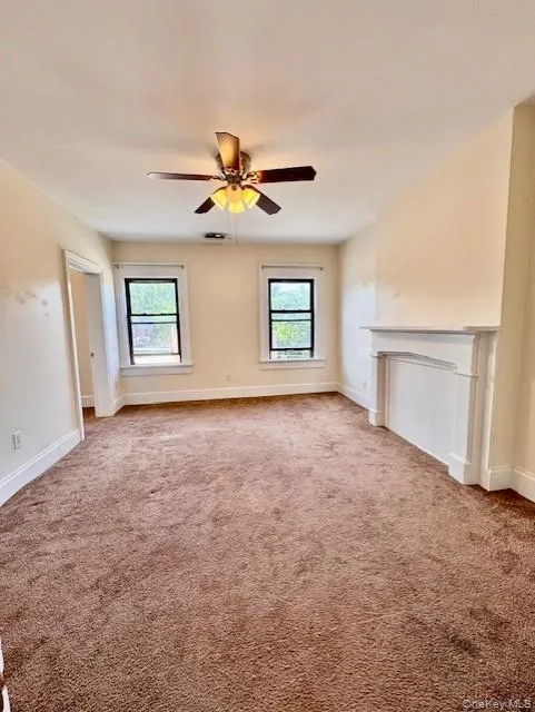 Unfurnished living room with healthy amount of natural light, carpet floors, and ceiling fan Unfurnished living room with healthy amount of natural light, carpet floors, and ceiling fan