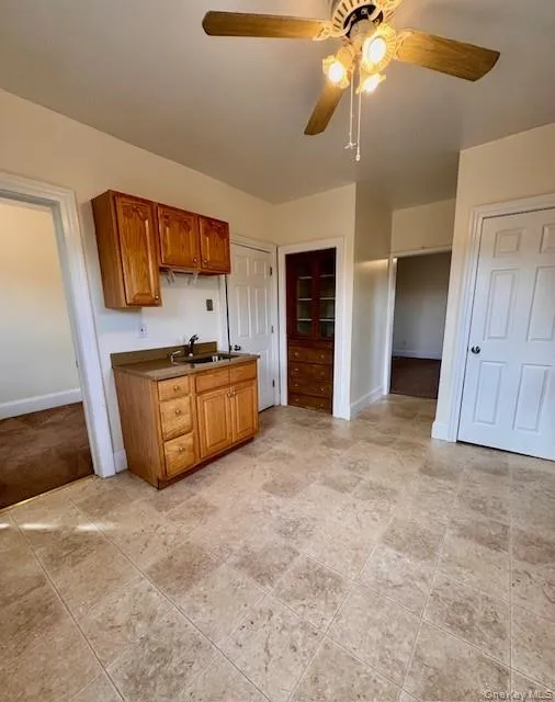 Kitchen with a ceiling fan, brown cabinets, and dark countertops Kitchen with a ceiling fan, brown cabinets, and dark countertops