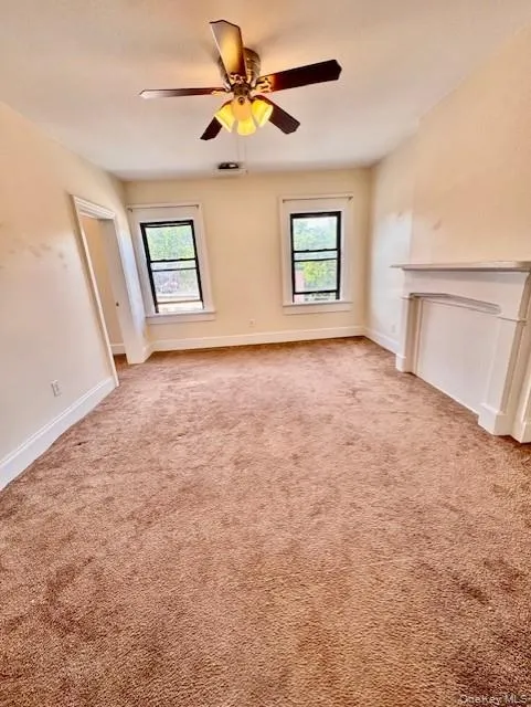 Unfurnished living room with plenty of natural light, a ceiling fan, and light colored carpet Unfurnished living room with plenty of natural light, a ceiling fan, and light colored carpet