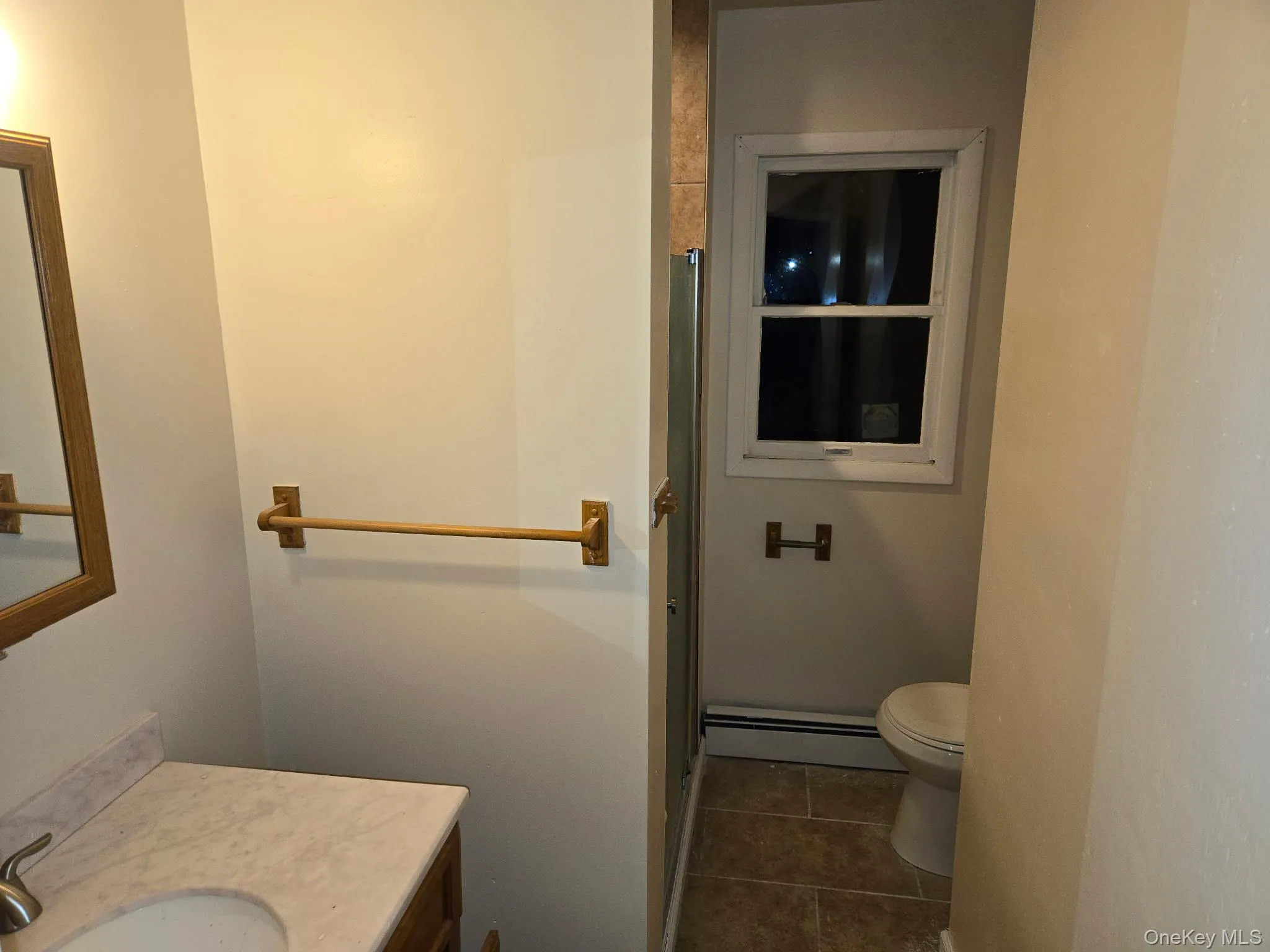 Bathroom featuring vanity, dark tile patterned flooring, and a baseboard heating unit Bathroom featuring vanity, dark tile patterned flooring, and a baseboard heating unit