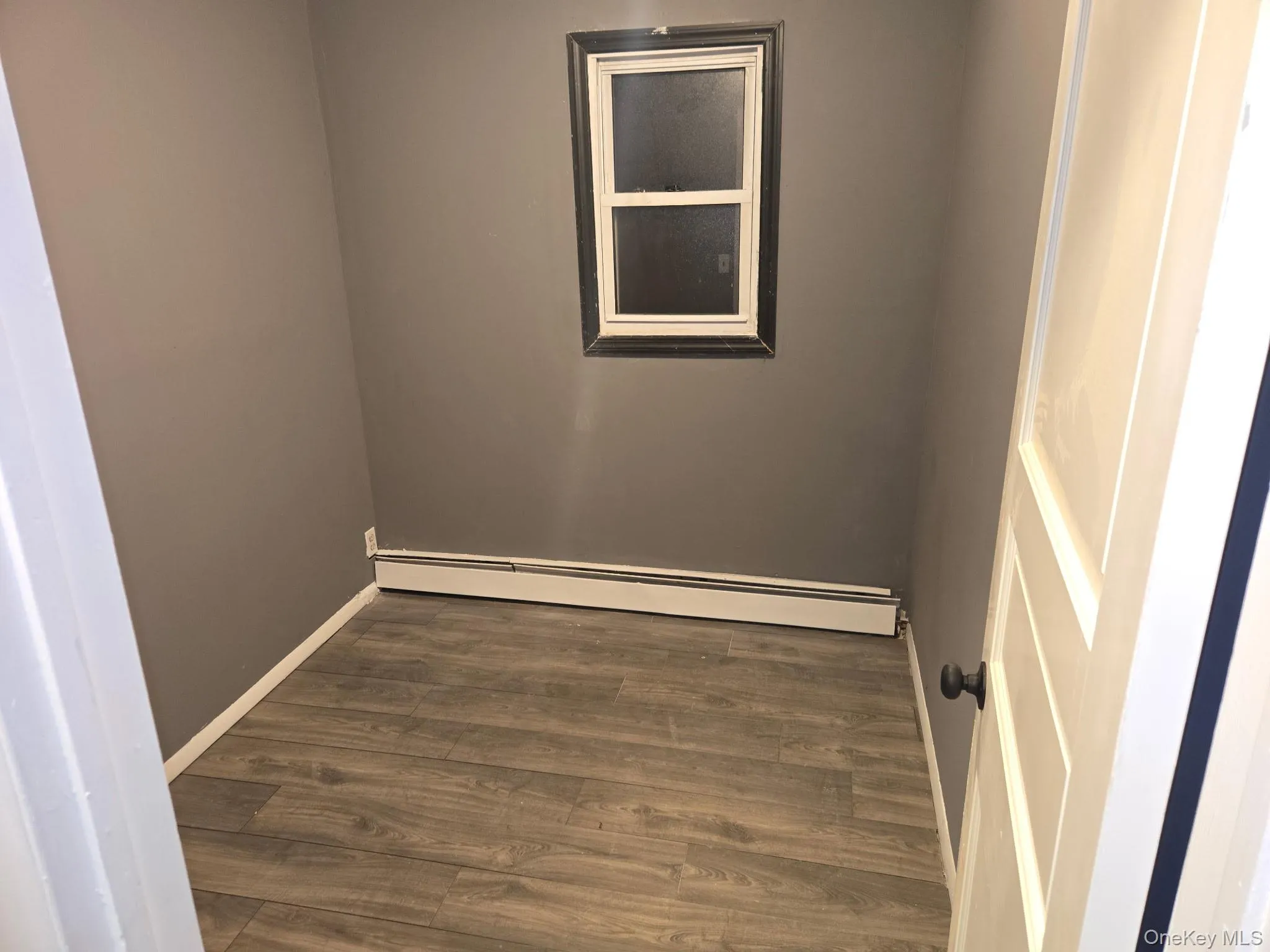 Bedroom featuring a baseboard heating unit and dark wood-type flooring Bedroom featuring a baseboard heating unit and dark wood-type flooring