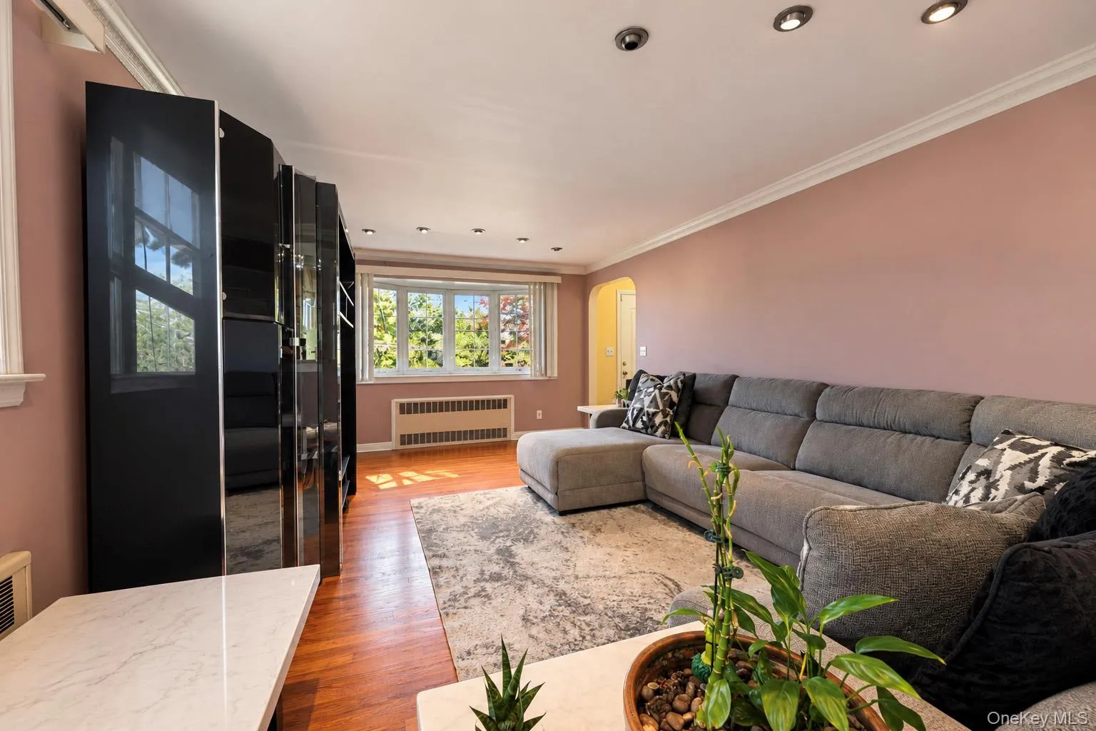Living area featuring wood-finish flooring, recessed lighting, crown molding, and a bay window Living area featuring wood-finish flooring, recessed lighting, crown molding, and a bay window