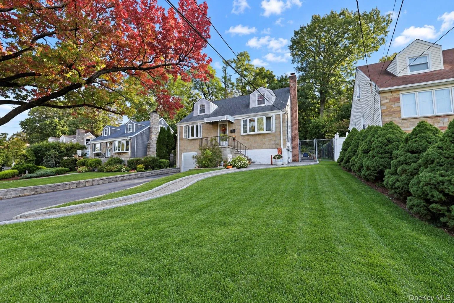 Stone and shingle exterior featuring a gabled roofline, dormer windows, an exterior brick chimney, and a paver walkway Stone and shingle exterior featuring a gabled roofline, dormer windows, an exterior brick chimney, and a paver walkway