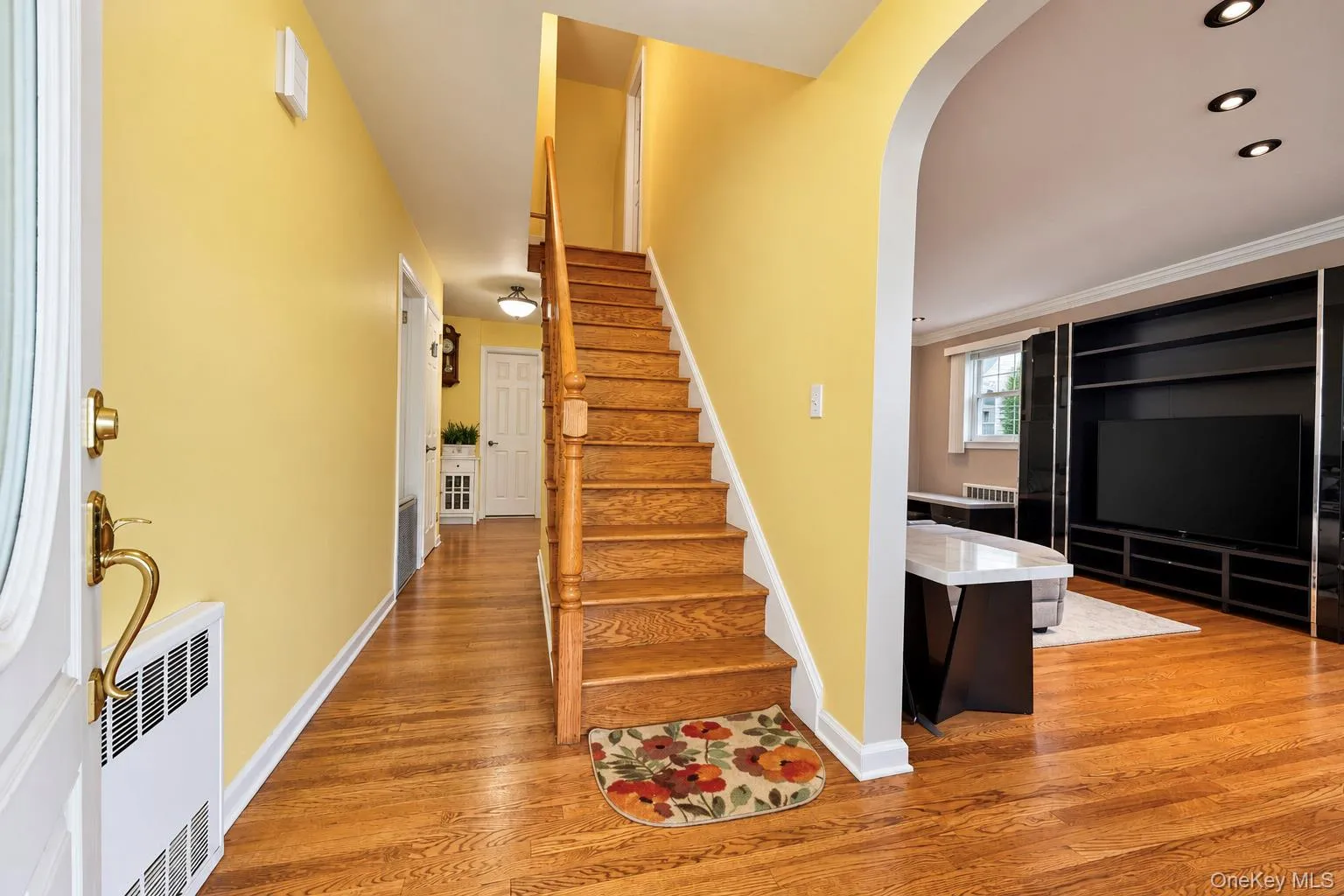 Hallway featuring wood-finish flooring, a wood staircase with a turned balustrade, arched entryway, and recessed lighting Hallway featuring wood-finish flooring, a wood staircase with a turned balustrade, arched entryway, and recessed lighting