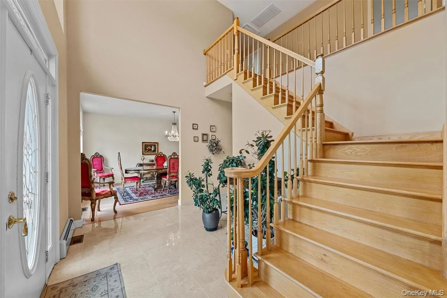 Foyer with suspended lighting, a high ceiling, and a baseboard heating unit Foyer with suspended lighting, a high ceiling, and a baseboard heating unit