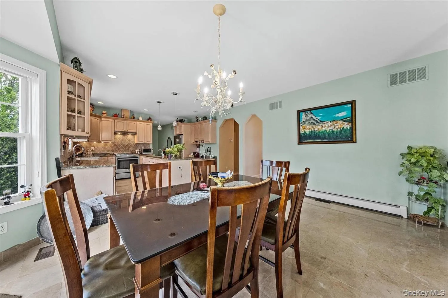 Dining room featuring arched walkways, suspended lighting, and a baseboard heating unit Dining room featuring arched walkways, suspended lighting, and a baseboard heating unit