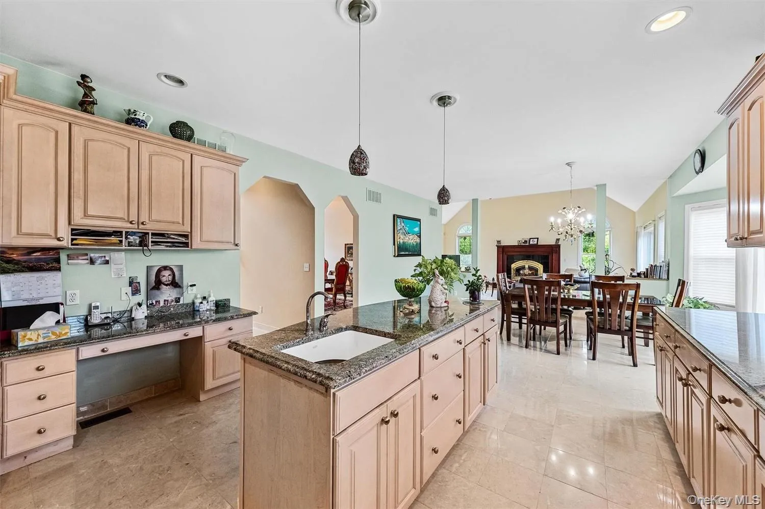 Kitchen with light wood finish cabinets, dark stone counters, arched walkways, and vaulted ceiling Kitchen with light wood finish cabinets, dark stone counters, arched walkways, and vaulted ceiling