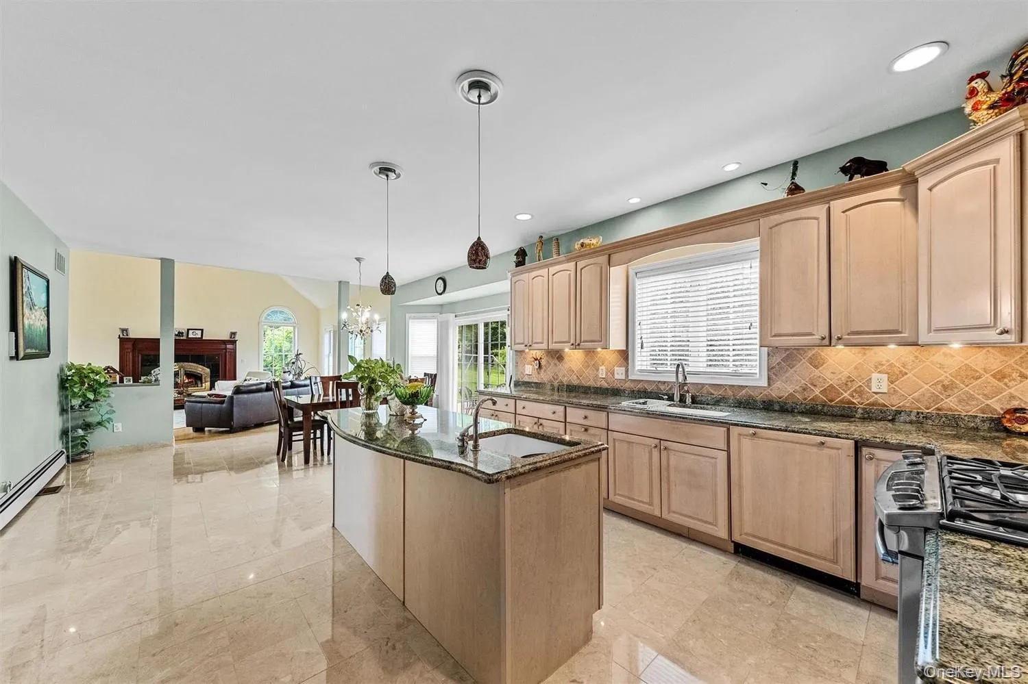 Kitchen featuring light wood finish cabinets, dark stone counters, paneled dishwasher, gas stove, and a center island Kitchen featuring light wood finish cabinets, dark stone counters, paneled dishwasher, gas stove, and a center island