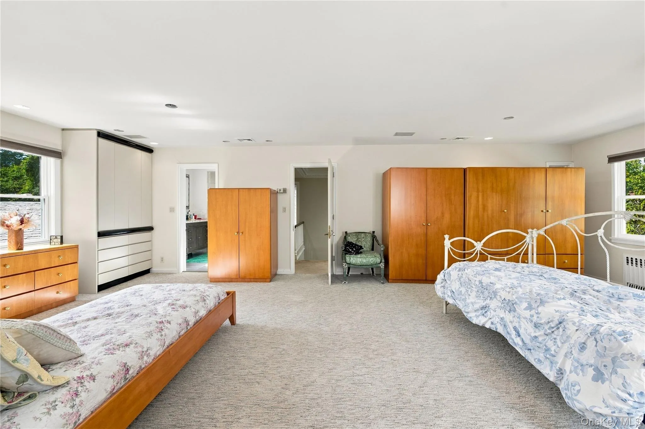 Spacious room featuring neutral carpeting, recessed lighting, double-hung windows, and built-in floor-to-ceiling cabinetry Spacious room featuring neutral carpeting, recessed lighting, double-hung windows, and built-in floor-to-ceiling cabinetry