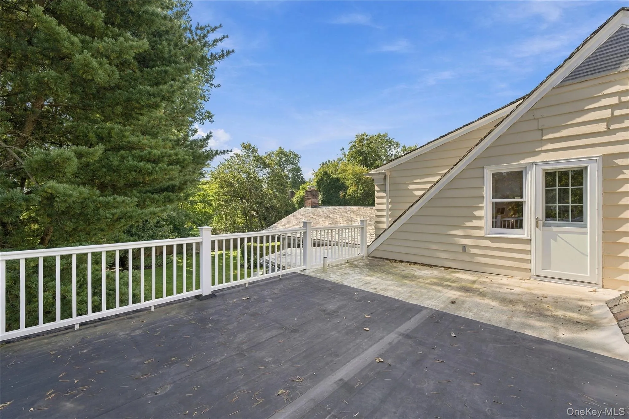 Elevated outdoor terrace featuring white picket-style railing, light-colored horizontal siding, and a multi-pane glass door Elevated outdoor terrace featuring white picket-style railing, light-colored horizontal siding, and a multi-pane glass door