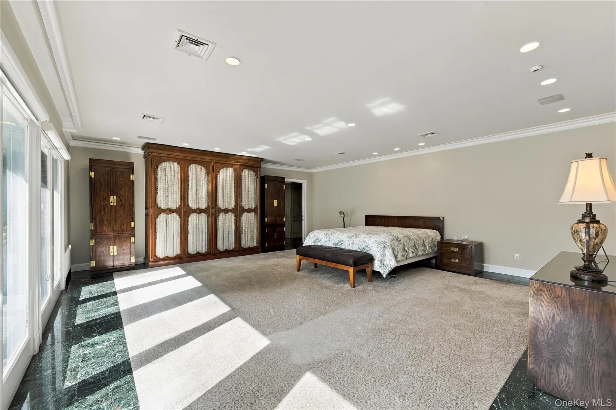 Expansive room featuring built-in floor-to-ceiling wooden cabinetry, polished stone flooring, recessed ceiling lighting, and sliding glass doors Expansive room featuring built-in floor-to-ceiling wooden cabinetry, polished stone flooring, recessed ceiling lighting, and sliding glass doors