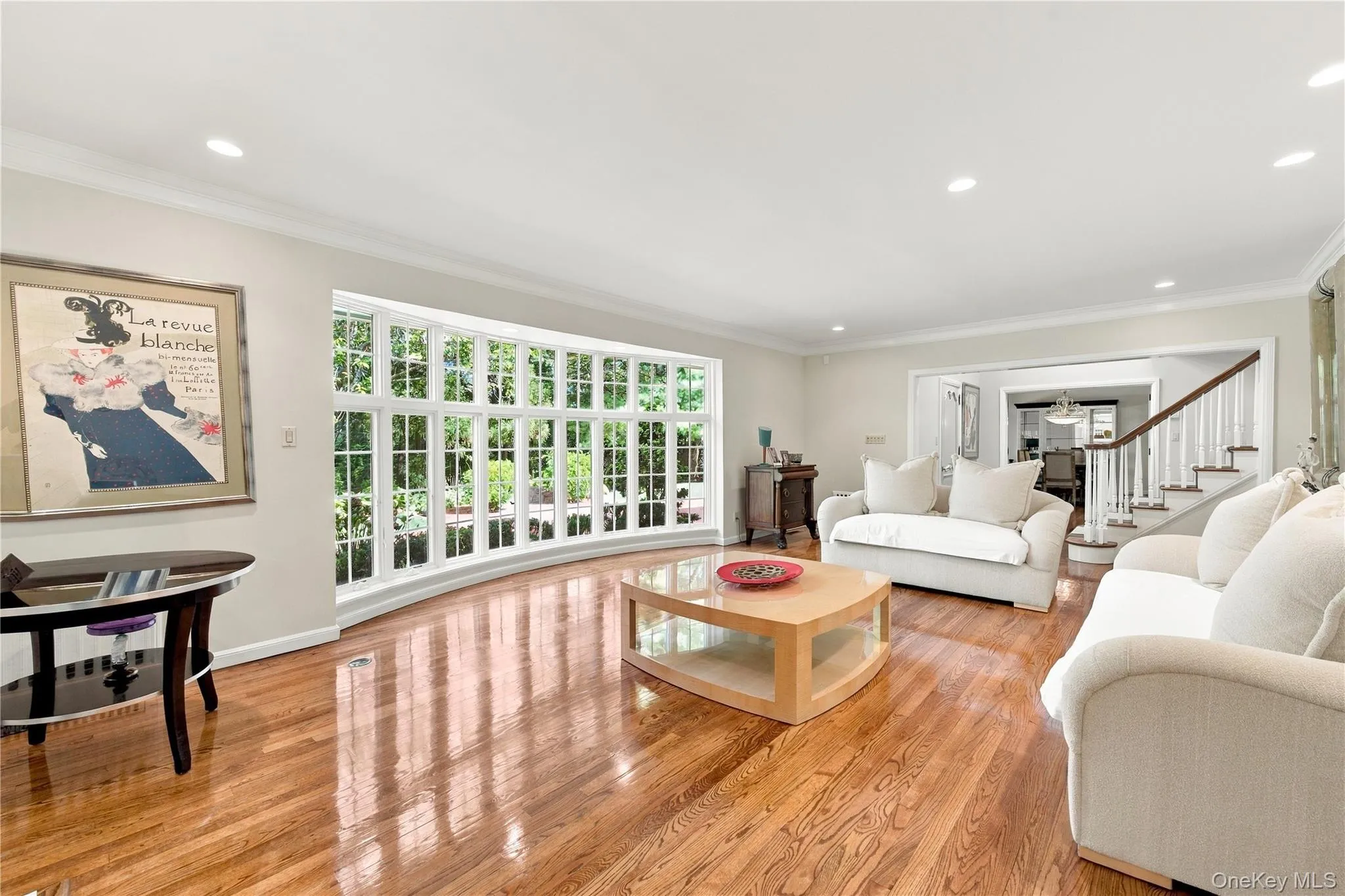 Spacious room featuring wood-finish flooring, recessed lighting, crown molding, and a large multi-pane bay window Spacious room featuring wood-finish flooring, recessed lighting, crown molding, and a large multi-pane bay window