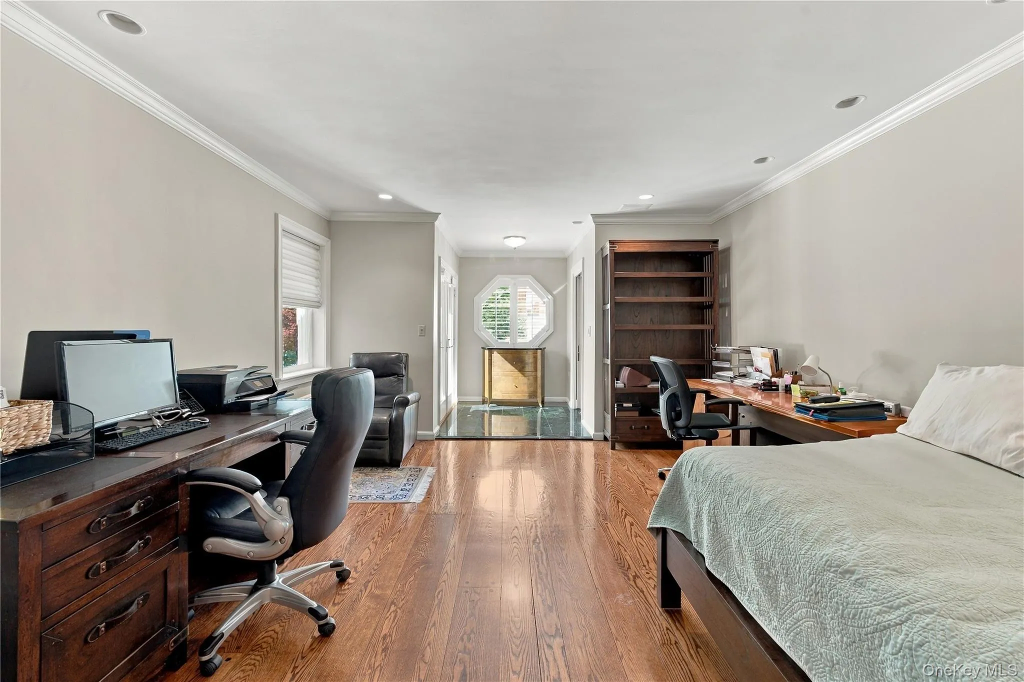 Spacious room featuring wood-finish flooring, recessed lighting, crown molding, and an octagonal accent window Spacious room featuring wood-finish flooring, recessed lighting, crown molding, and an octagonal accent window