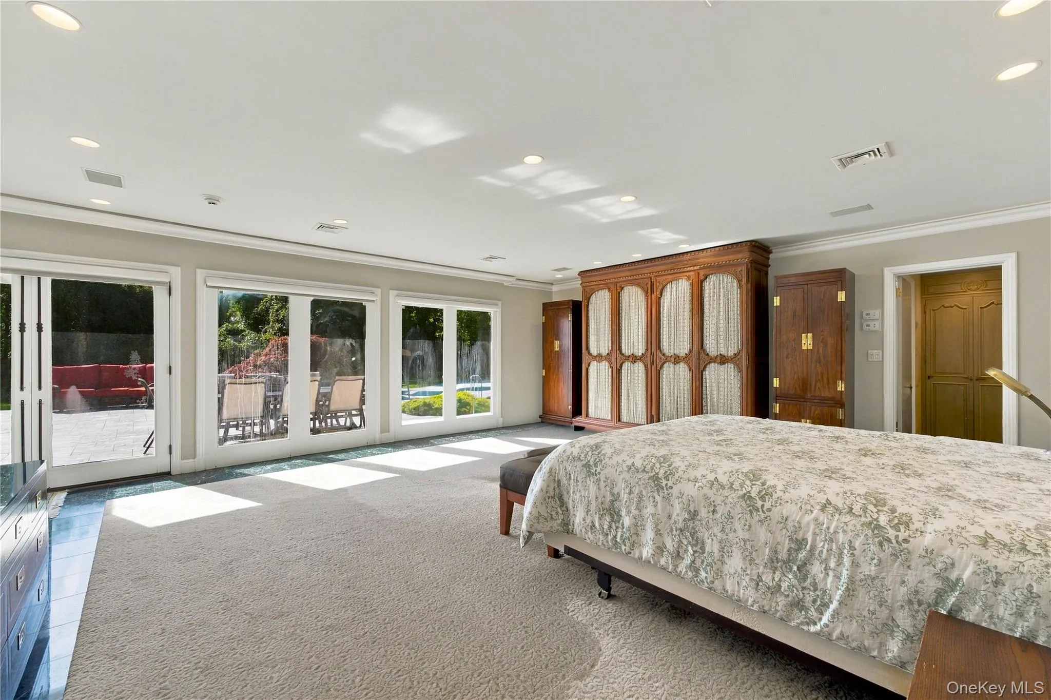 Spacious room with neutral wall-to-wall carpeting, recessed ceiling lighting, three sets of glass patio doors, and built-in wood cabinetry Spacious room with neutral wall-to-wall carpeting, recessed ceiling lighting, three sets of glass patio doors, and built-in wood cabinetry