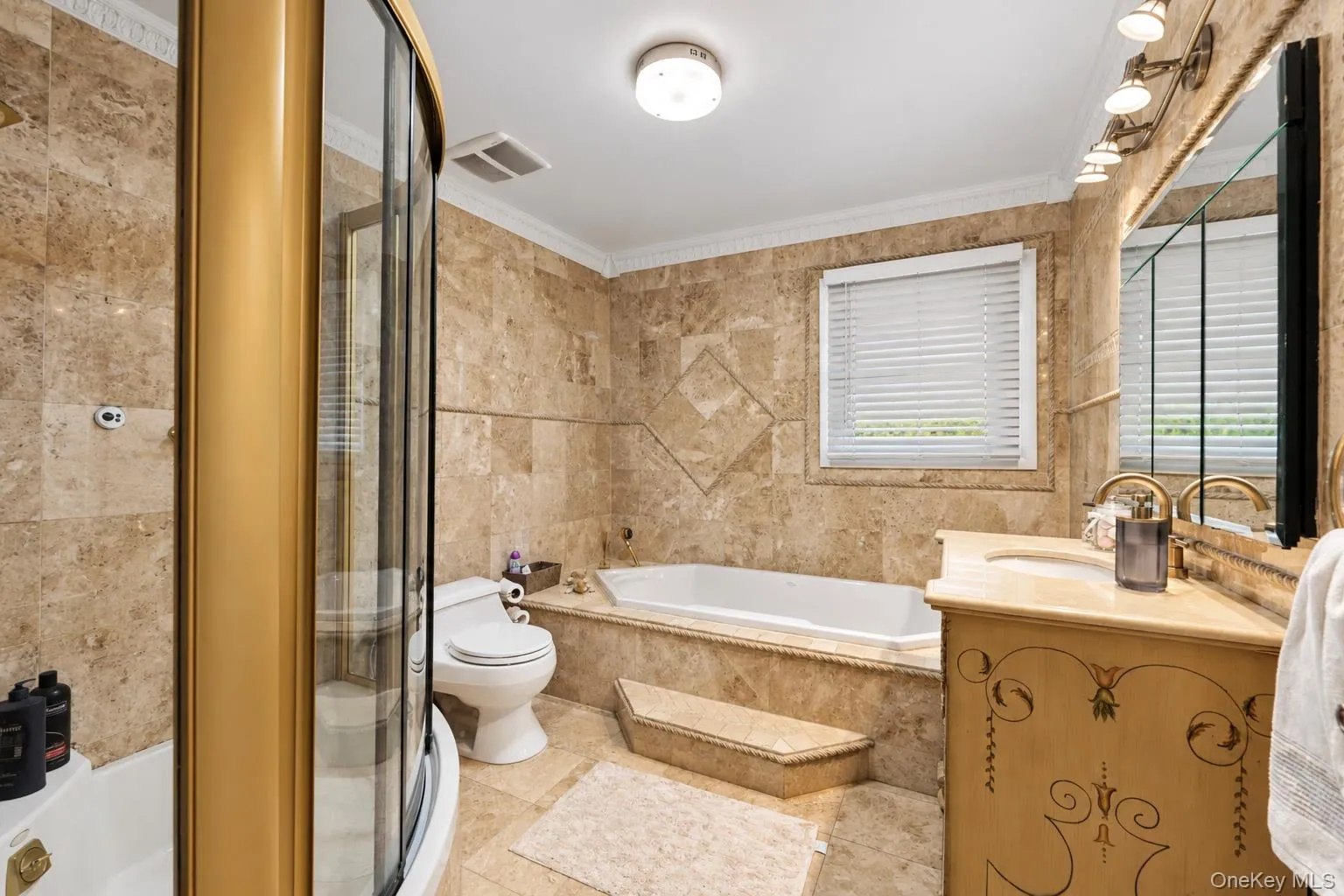 Bathroom featuring floor-to-ceiling stone tile, a glass-enclosed corner shower, a built-in soaking tub with a stone surround, and an integrated stone-top vanity Bathroom featuring floor-to-ceiling stone tile, a glass-enclosed corner shower, a built-in soaking tub with a stone surround, and an integrated stone-top vanity