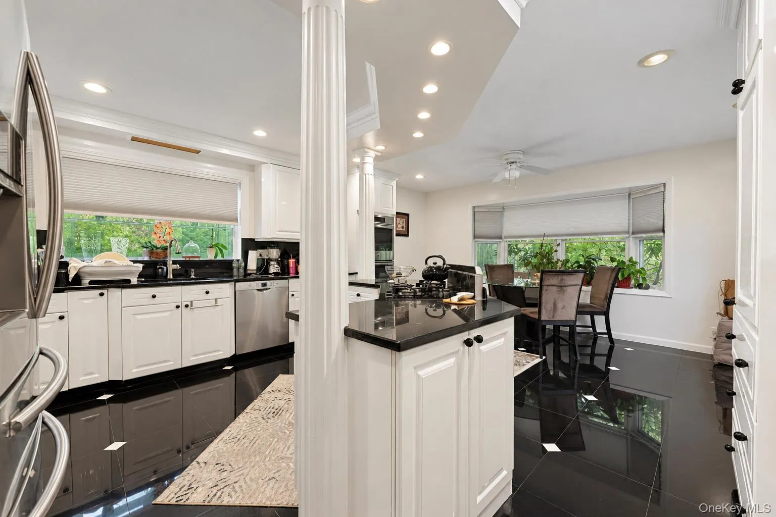 Kitchen featuring white cabinetry, dark stone countertops, stainless steel appliances, recessed lighting, and black tile flooring Kitchen featuring white cabinetry, dark stone countertops, stainless steel appliances, recessed lighting, and black tile flooring