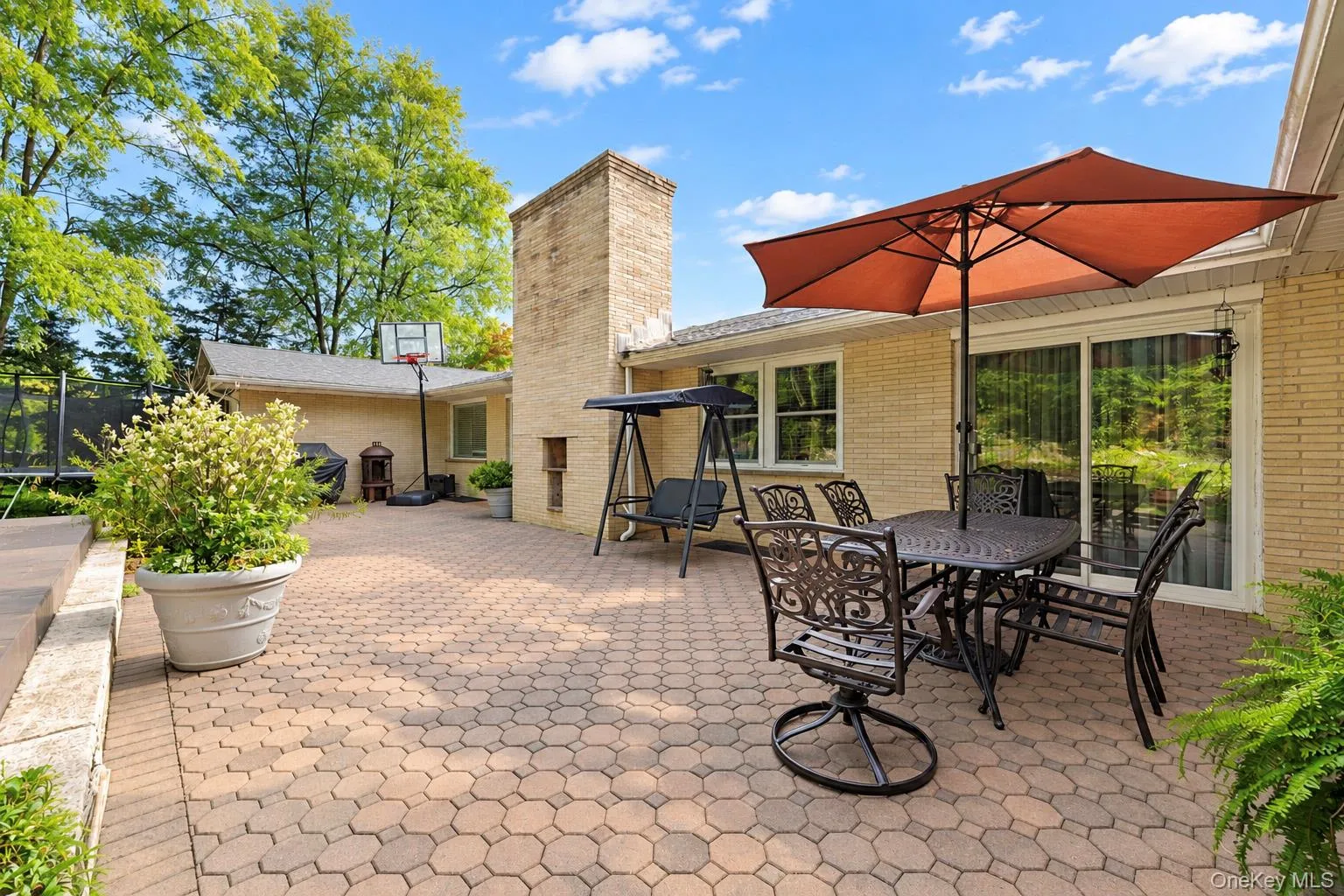 Spacious brick patio featuring a masonry chimney, sliding glass doors, and light-colored brick exterior siding Spacious brick patio featuring a masonry chimney, sliding glass doors, and light-colored brick exterior siding