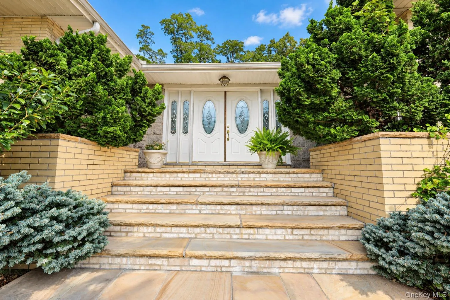Double front doors with oval decorative glass inserts, brick-accented stone steps, and raised brick planters Double front doors with oval decorative glass inserts, brick-accented stone steps, and raised brick planters