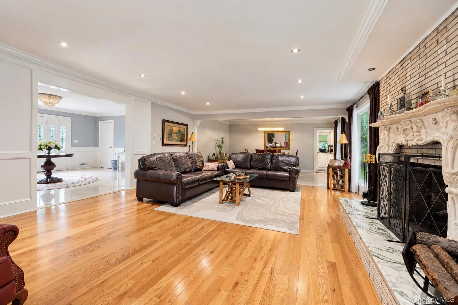 Living area featuring wood-finish flooring, an ornate fireplace mantel, stone hearth, recessed lighting, and crown molding Living area featuring wood-finish flooring, an ornate fireplace mantel, stone hearth, recessed lighting, and crown molding