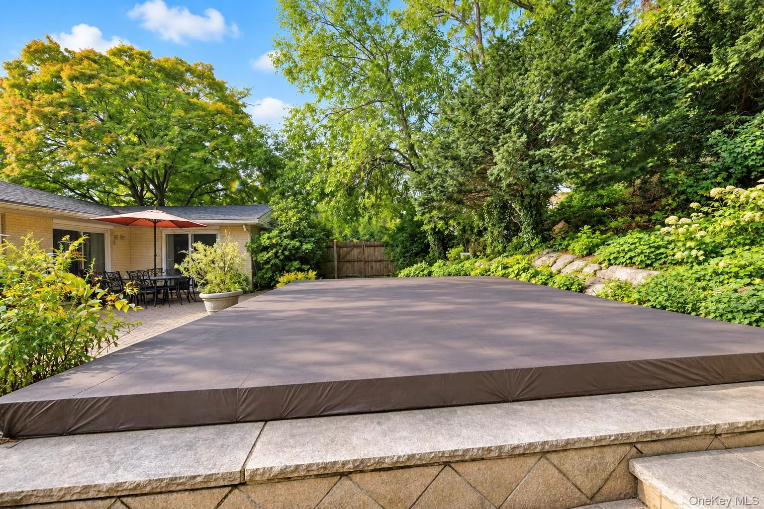 Stone-paved patio area with stone-retaining wall features and mature landscaping Stone-paved patio area with stone-retaining wall features and mature landscaping