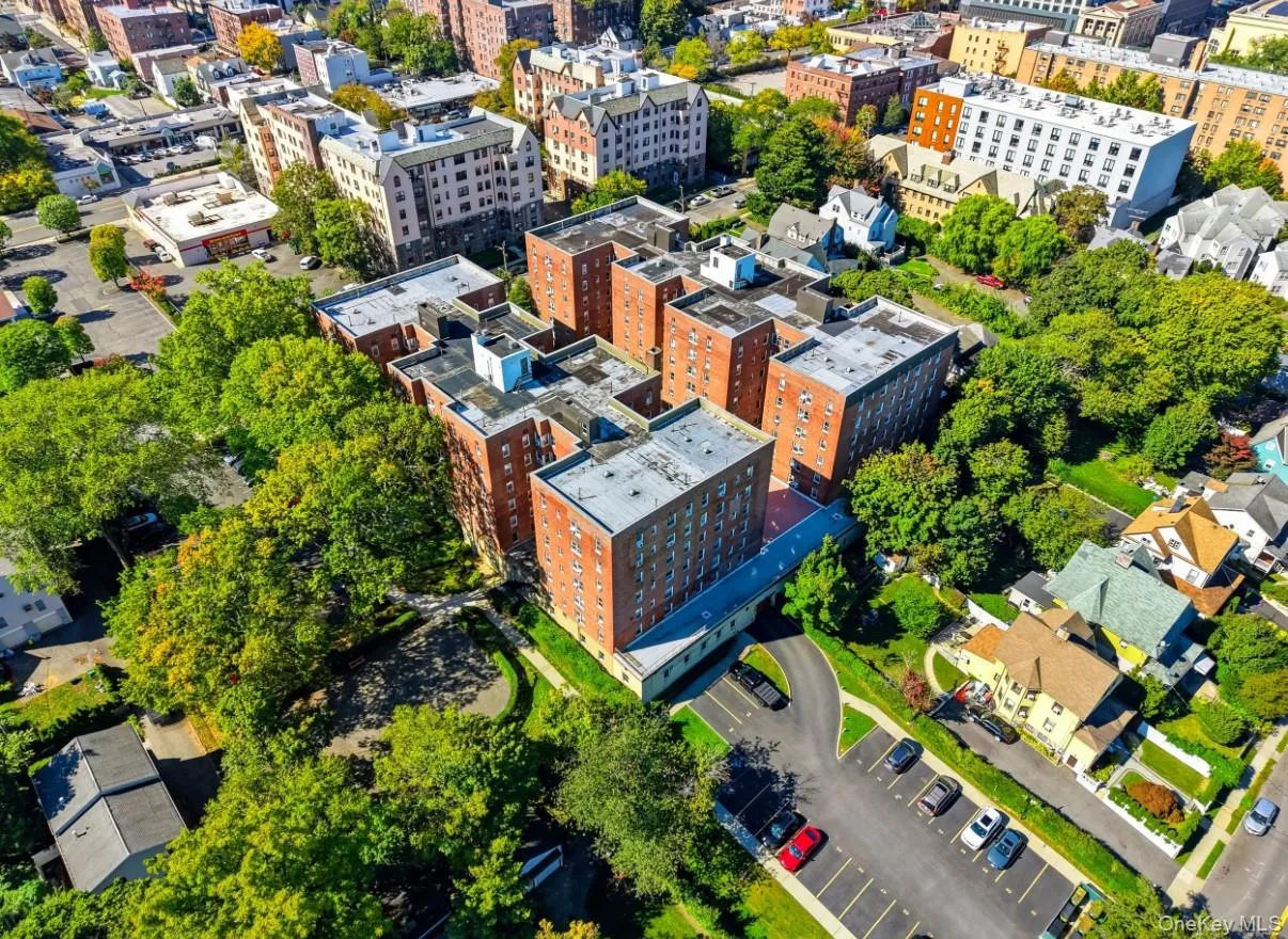 Multi-story brick exterior building featuring a paved parking lot and mature tree canopy Multi-story brick exterior building featuring a paved parking lot and mature tree canopy