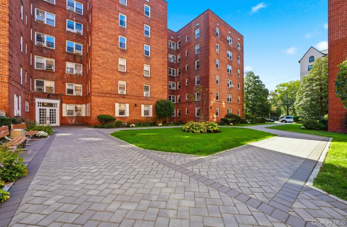 Multi-story red brick exterior featuring herringbone-patterned paver walkways, a central manicured lawn, and white-framed multi-pane windows Multi-story red brick exterior featuring herringbone-patterned paver walkways, a central manicured lawn, and white-framed multi-pane windows