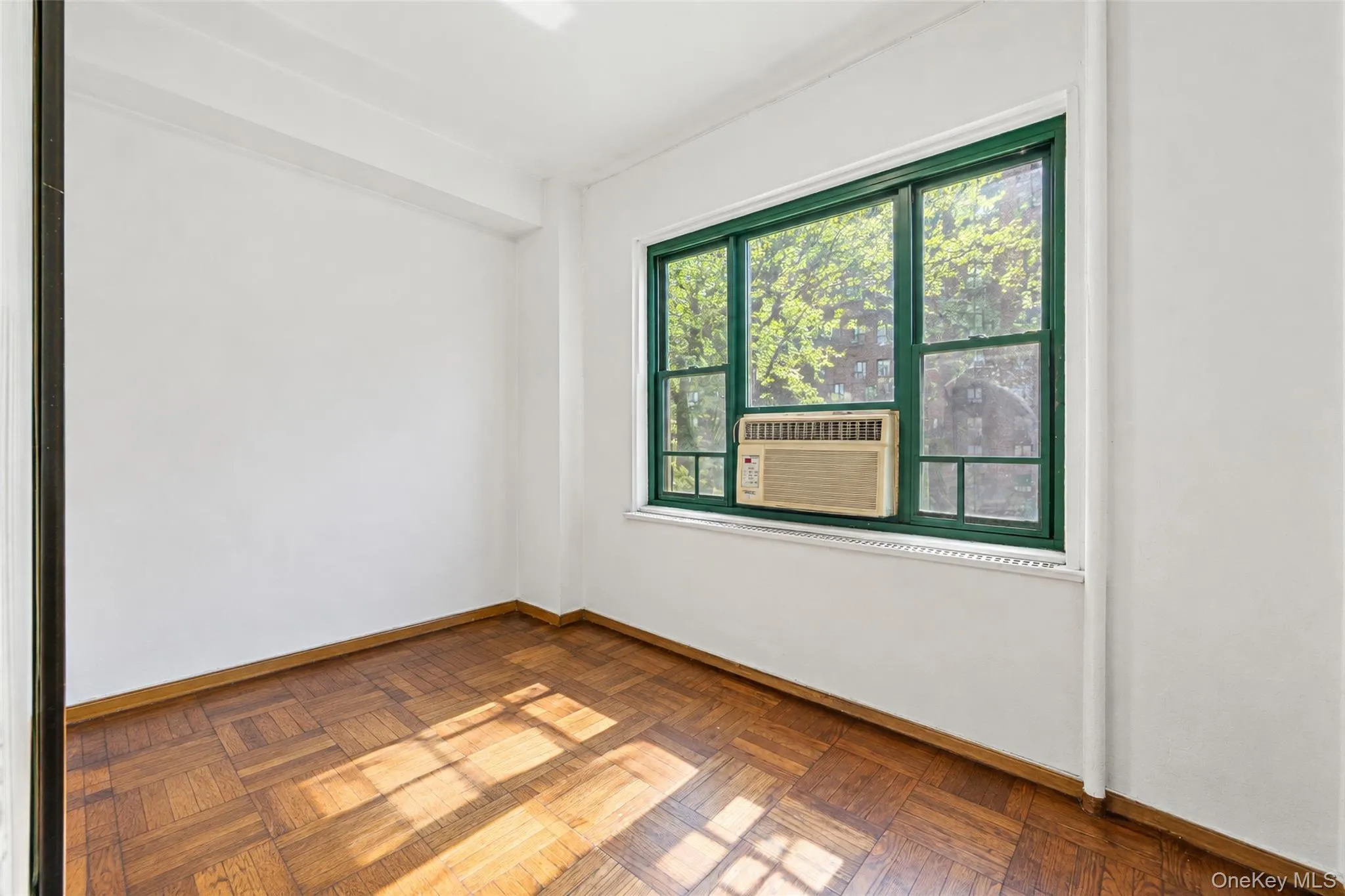 Parquet wood-finish flooring, white walls, and a large multi-pane window with dark green framing Parquet wood-finish flooring, white walls, and a large multi-pane window with dark green framing
