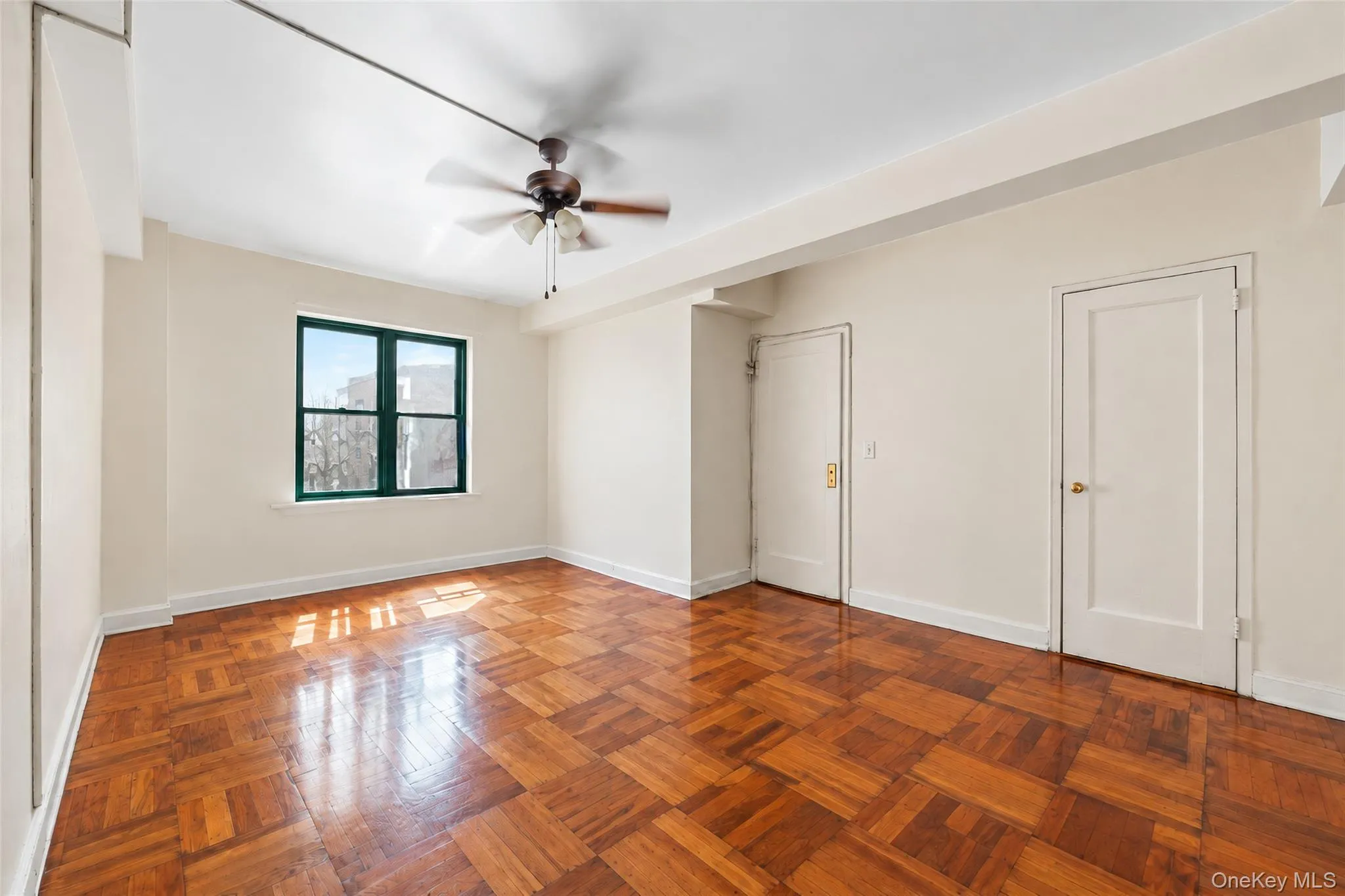 Parquet wood-finish flooring, multi-pane window with dark trim, and a ceiling-mounted light fixture with a three-blade fan Parquet wood-finish flooring, multi-pane window with dark trim, and a ceiling-mounted light fixture with a three-blade fan