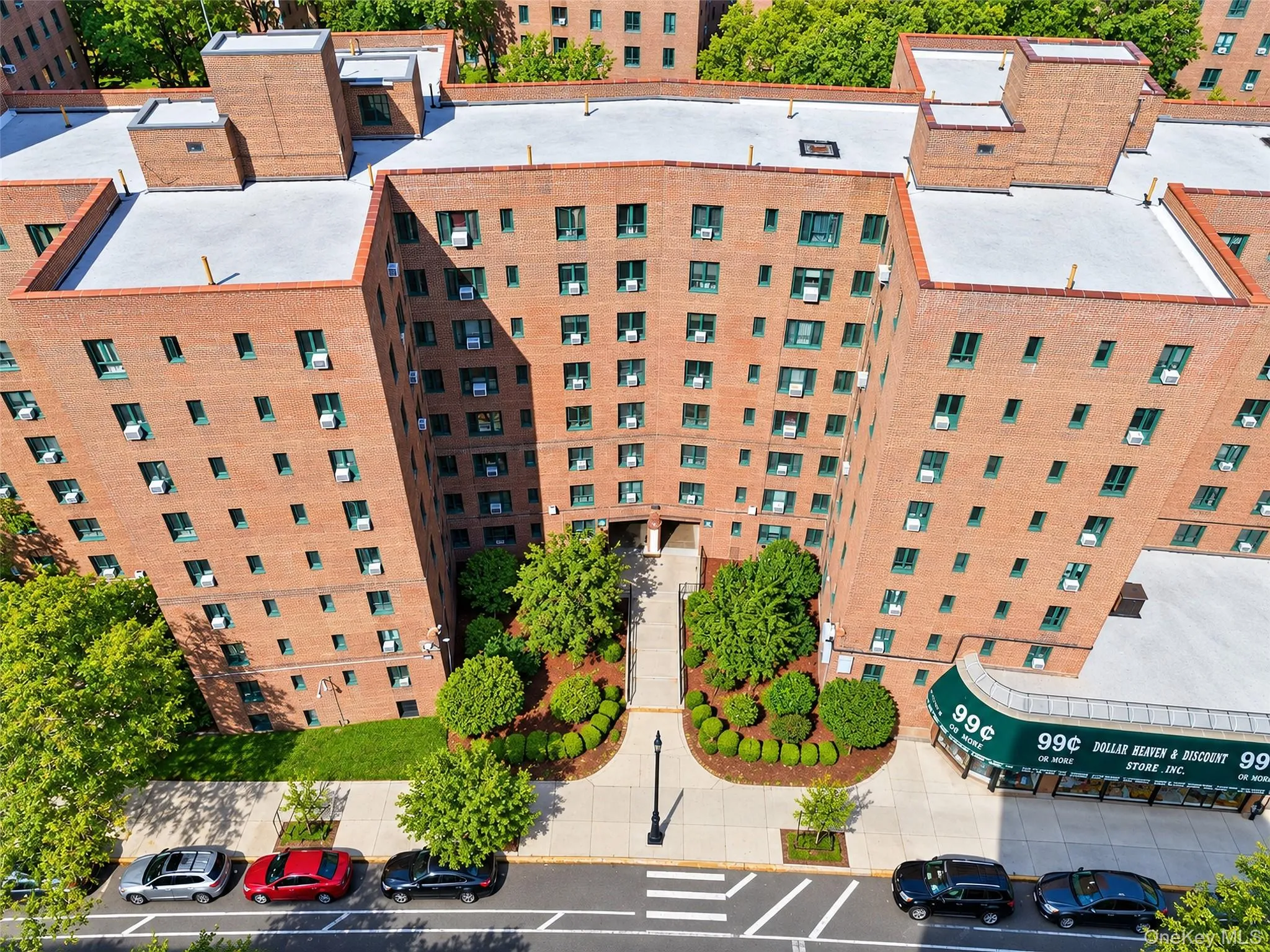 Multi-story brick exterior featuring a U-shaped architectural design, concrete walkways, landscaped green space, and mature trees Multi-story brick exterior featuring a U-shaped architectural design, concrete walkways, landscaped green space, and mature trees