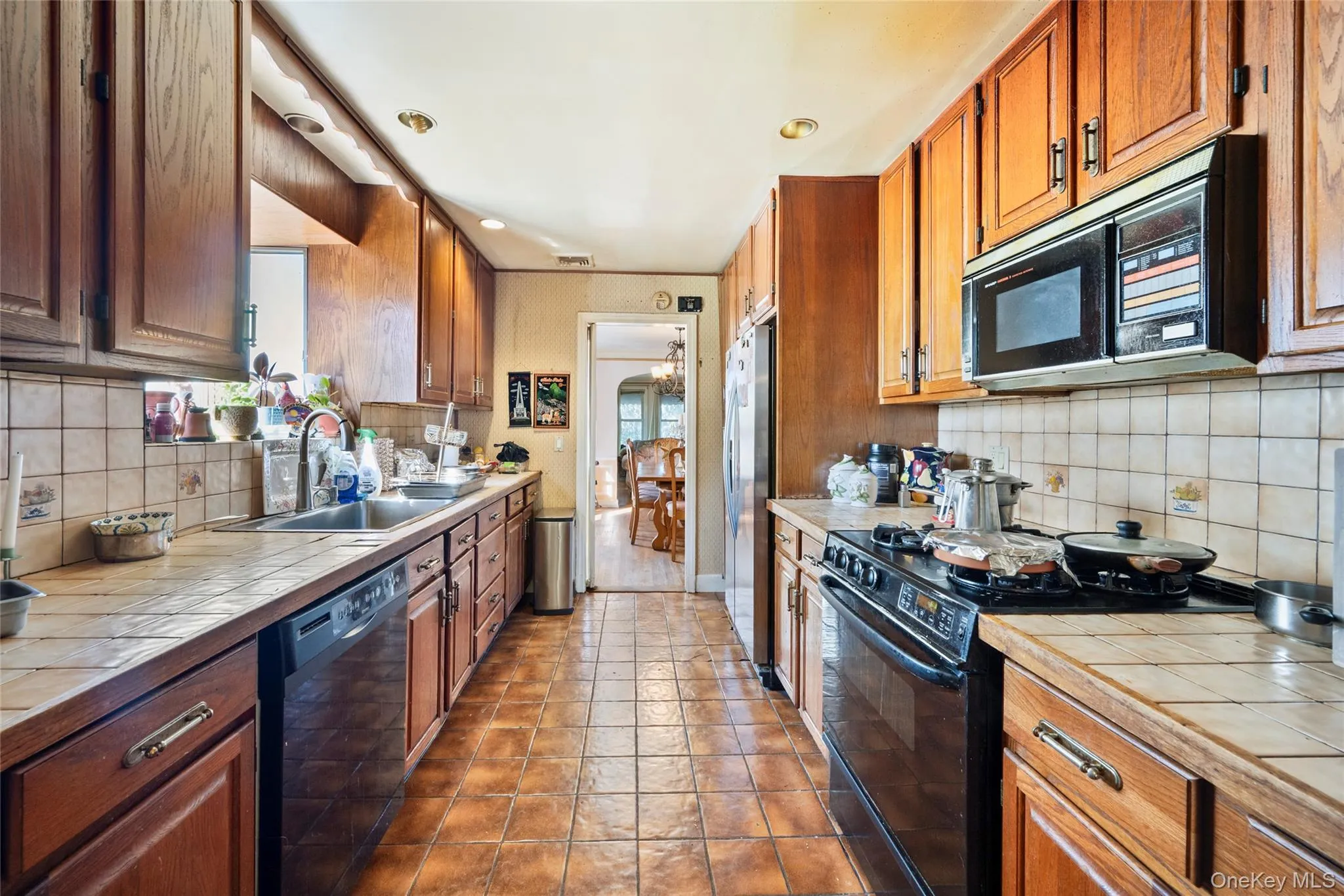 Kitchen featuring wood cabinetry, tile countertops, tile flooring, recessed lighting, and built-in appliances Kitchen featuring wood cabinetry, tile countertops, tile flooring, recessed lighting, and built-in appliances