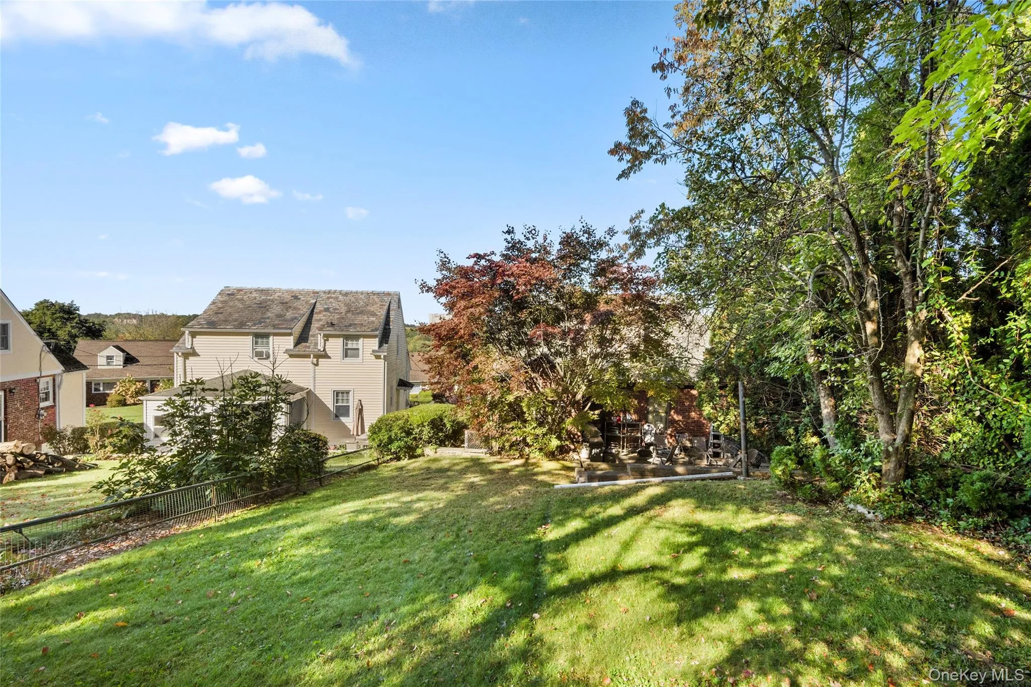 Expansive sloped lawn featuring mature deciduous trees and established perimeter landscaping Expansive sloped lawn featuring mature deciduous trees and established perimeter landscaping