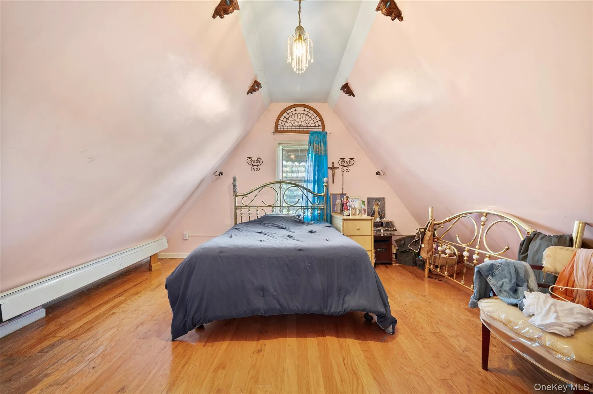 Second floor BR3: Vaulted ceiling bedroom featuring hardwood flooring, arched window detailing, and a classic crystal-style pendant light fixture Second floor BR3: Vaulted ceiling bedroom featuring hardwood flooring, arched window detailing, and a classic crystal-style pendant light fixture