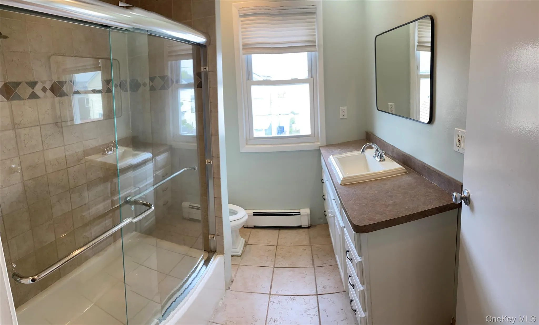 Bathroom featuring vanity, a baseboard radiator, tile patterned floors, and enclosed tub / shower combo Bathroom featuring vanity, a baseboard radiator, tile patterned floors, and enclosed tub / shower combo