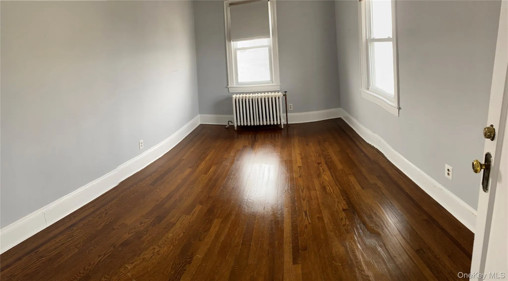 Empty room featuring radiator and dark wood-style floors Empty room featuring radiator and dark wood-style floors